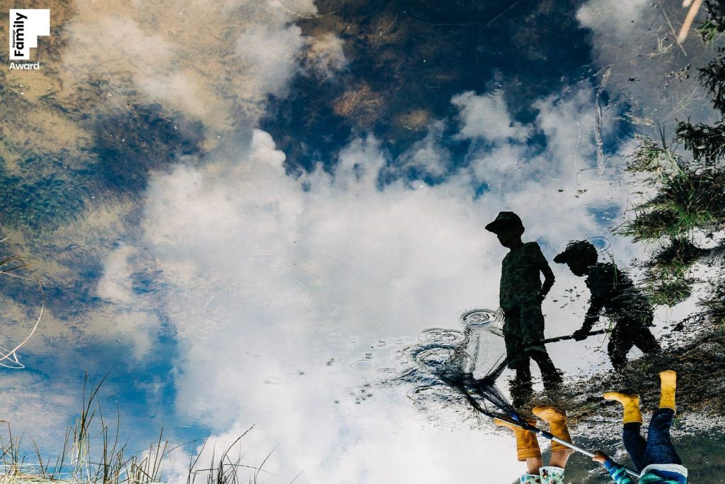 Spiegelung zweier Kinder in einem See mit Wolken I Sabine Doppelhofer Familienfotografie