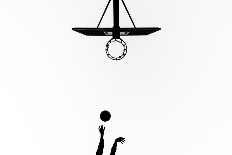 Ein Basketballkorb ist in schwarz weiss mit 2 Händen und einem Ball von unten zu sehen I Modern documentary family photography